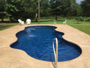 A newly constructed in-ground pool with pool furniture.